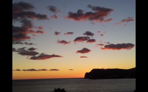 Bild: durch Abendstimmung rot gefärbte Wolken ziehen über das Meer